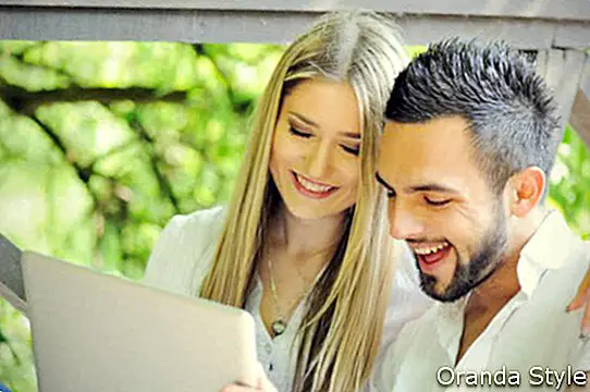 Vyras ir moteris nešiojamąjį kompiuterį naudoja lauke