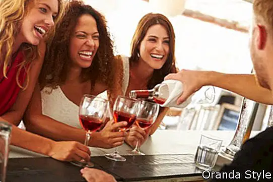 Tři kamarádky, kteří požívají pití na venkovní bar