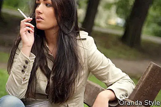 Mujer joven fumar en el parque