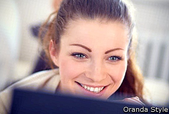 אישה צעירה ויפה עם מחשב נייד בזמן שאתה נרגע על הספה