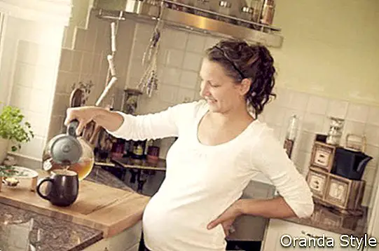 бременна жена, приготвяща чай у дома