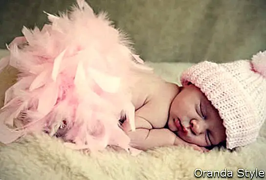 roosa mütsi ja roosa sulgi boa seljas magav beebitüdruk