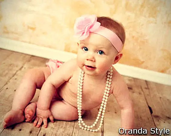 Rozkošná mladá holčička na sobě vintage perlový náhrdelník a růžová růžová čelenka