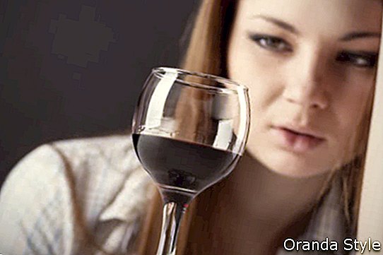 אישה צעירה ויפה בדיכאון שותה יין