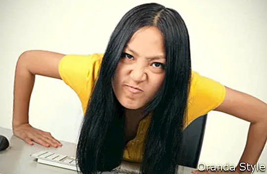 ילדה צעירה עושה פנים מרושעות בשולחן העבודה עם מחשב