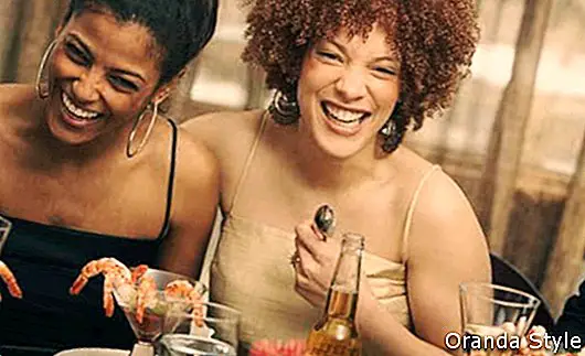 Zwei junge afrikanische Frauen lachen auf einer Dinnerparty