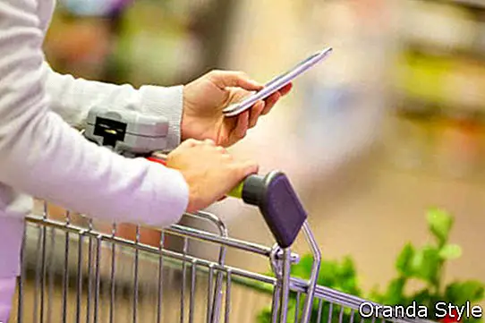Frau, die Handy beim Einkauf im Supermarkt verwendet
