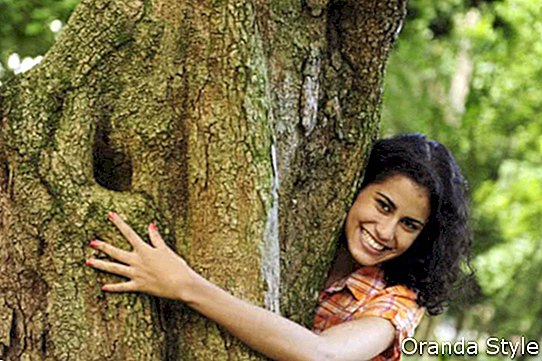 glückliche Frau, die einen Baum im Wald umarmt