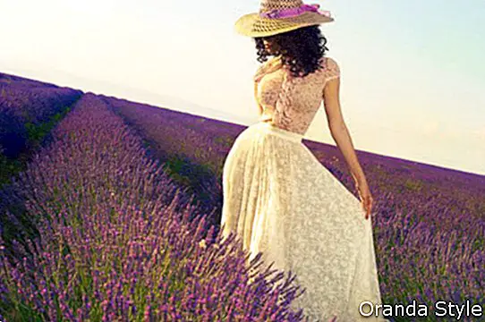 bella dama glamorosa de pie en un campo de flores de lavanda
