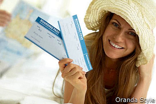 Eleganta sieviete cepurē, turot lidojuma biļetes
