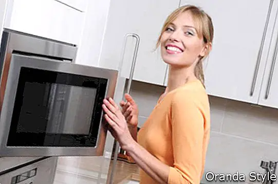 Mujer rubia cocinando con microondas en una cocina moderna