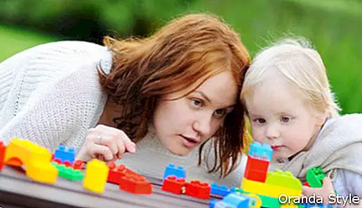 Mujer joven con su hijo pequeño jugando con coloridos bloques de plástico