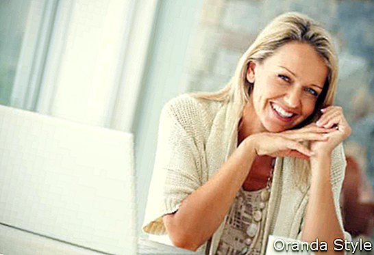 Smaidīga blondīne 40 gadu vecumā, izmantojot klēpjdatoru