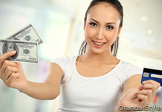 žena drží peníze a kreditní karty
