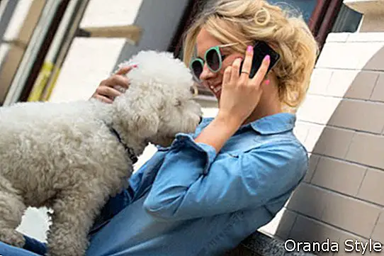 Симпатична блондинка с бяло куче Бишон Фризе