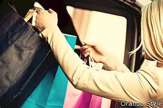 אישה בלונדינית מכניסה שקיות קניות במכונית