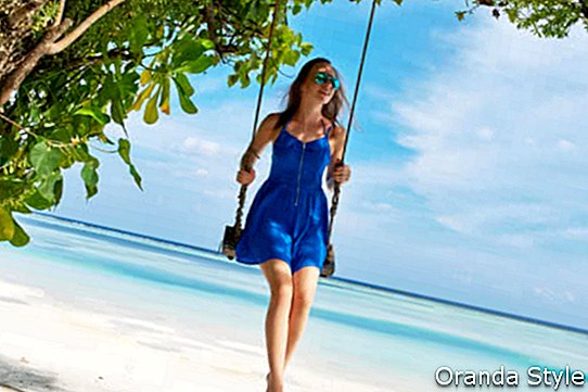 Kvinne i blå kjole som svinger på tropisk strand