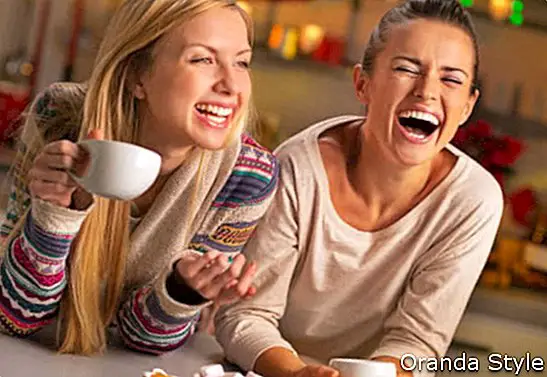 Портрет на смеещи се приятелки с коледни закуски в коледна украсена кухня