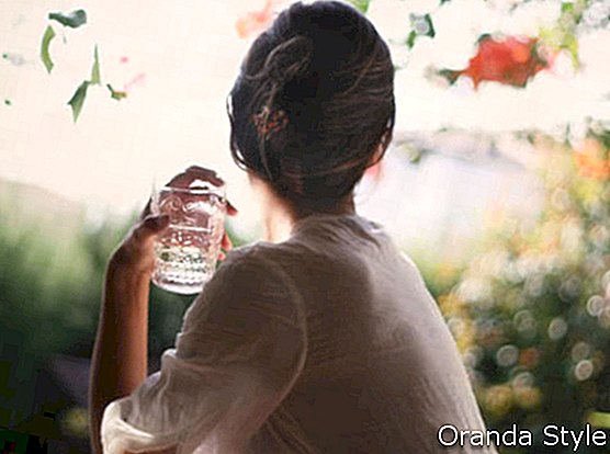 ženska gleda stran in drži kozarec vode