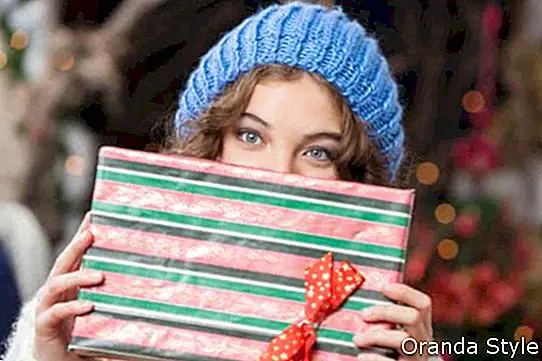 Портрет красива молода жінка, що охоплює обличчя з Різдвяний подарунок в магазині