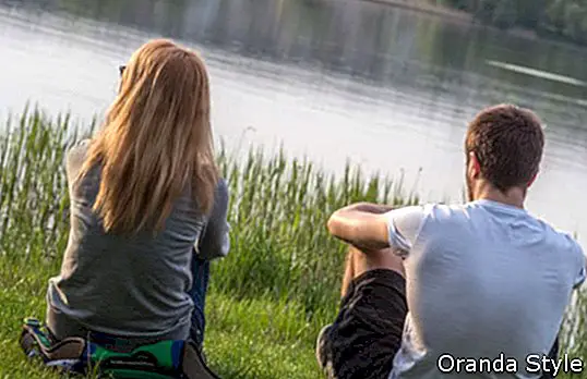 Berniukas ir mergaitė, sėdintys ant ežero kranto