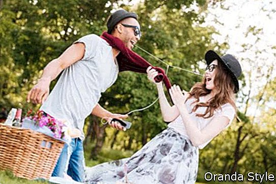 Glückliche junge Paare, die Spaß haben und Musik vom Smartphone auf Picknick hören