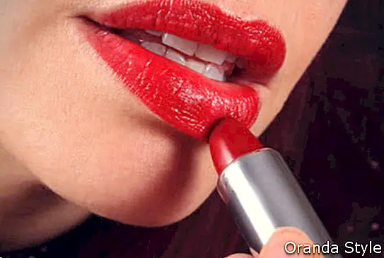 женщина наносит красную помаду на свои сочные губы