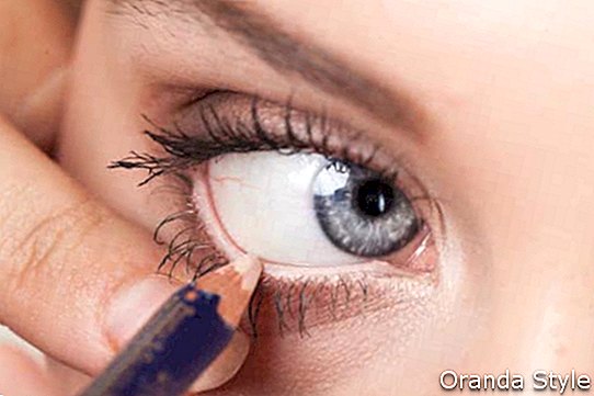 žena použití oční linky na oční víčko s tužkou