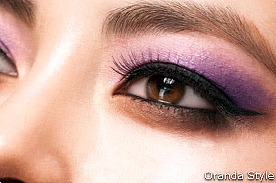 jaunos Azijos moters akis su ryškiai violetiniu makiažu