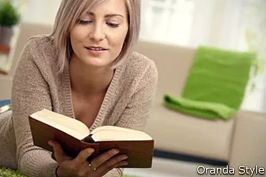 Молода жінка, читаючи книгу в домашніх умовах