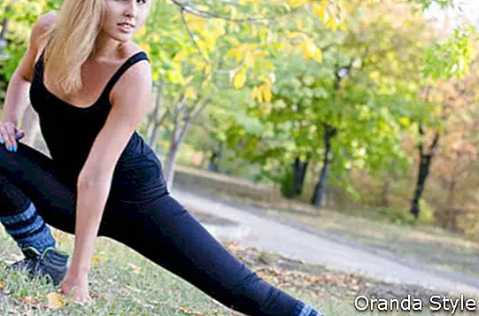 Атрактивна млада блондинка спортист загрява стречинг