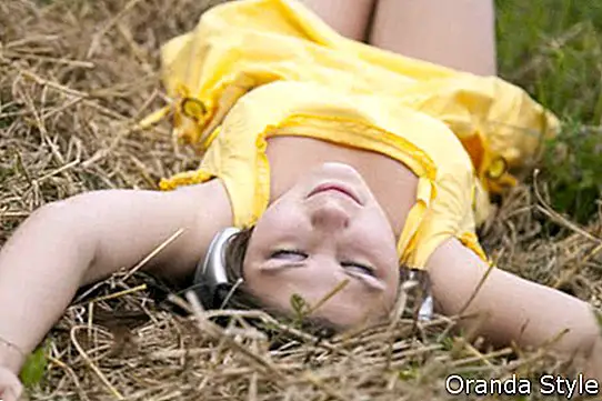 Jauna skaista meitene dzeltenā krāsā ar austiņām pie lauka