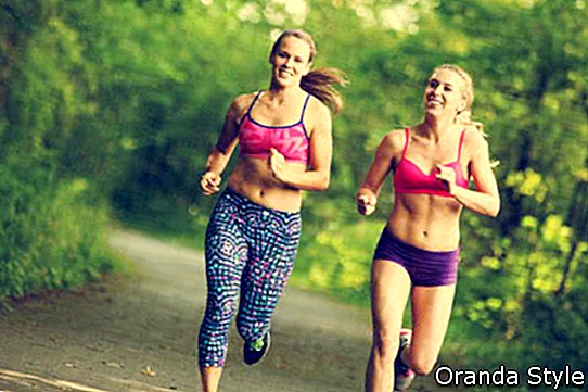 Kaks naist jooksevad sillutatud rajal läbi metsa