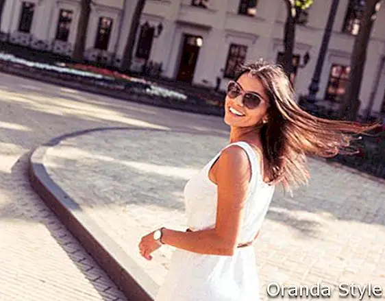 Mujer feliz en gafas de sol y vestido caminando al aire libre