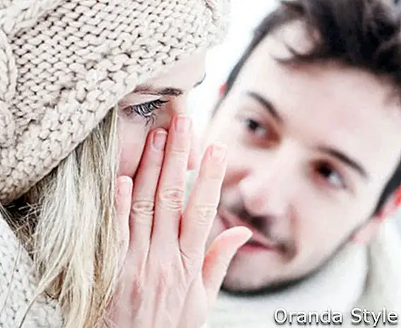 Kvinne som gråter nær mann om vinteren og tørker rive av ansiktet