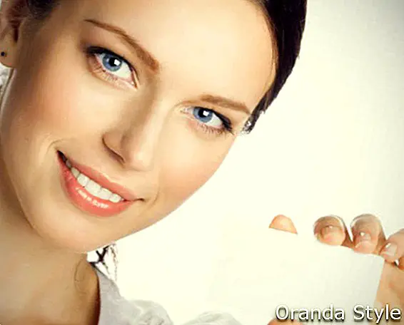 Žena s modrými očami drží vizitku