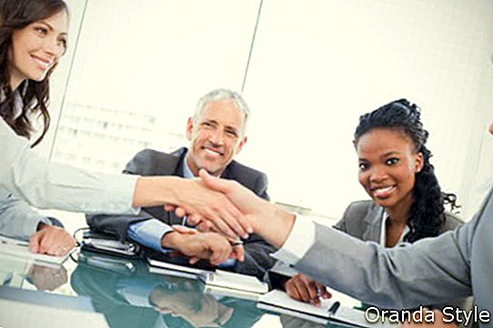 Joven empresaria y un compañero de trabajo dándose la mano durante una reunión