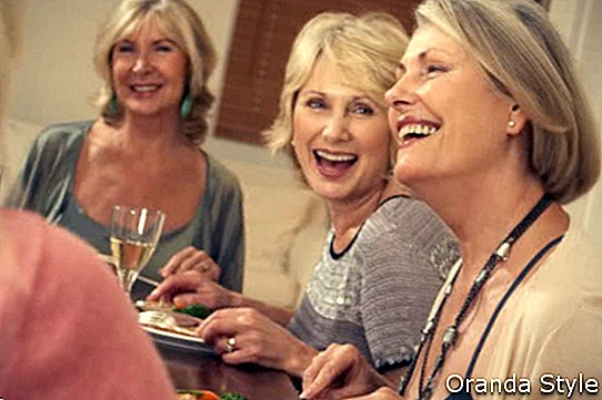 Mulher bebendo vinho na mesa de jantar com os amigos