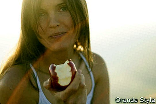 Hermosa joven comiendo una manzana roja en sol de la ensenada