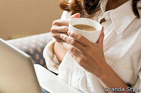 Žena, pití kávy a používání digitálních tabletu ráno
