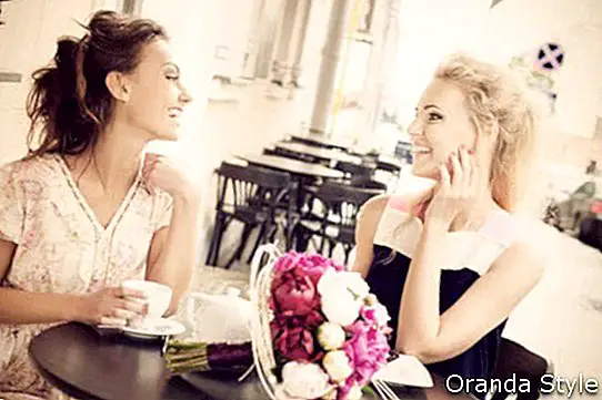 Dos hermosas mujeres jóvenes con gran sonrisa y peinado sentado en un bar.