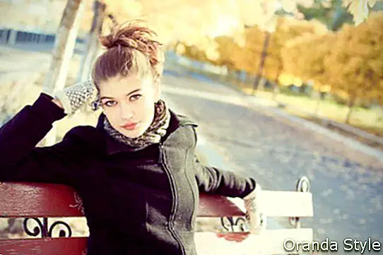 Красива млада жена брюнетка на пейка през есента