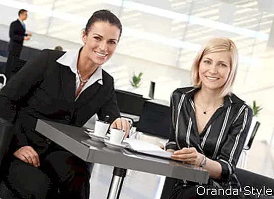 Glückliche Unternehmensgeschäftsfrauen, die am Couchtisch im Büro sich treffen