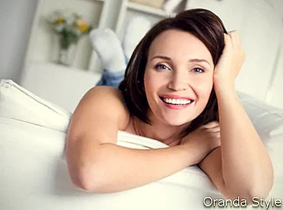 सोफा पर आराम करती मुस्कुराती महिला
