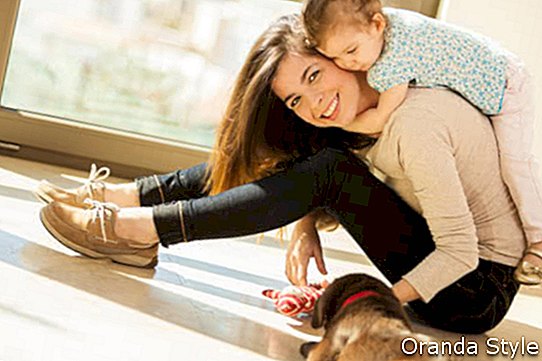 Красива млада испанска майка с момиченце и сладко кученце от лабрадор у дома