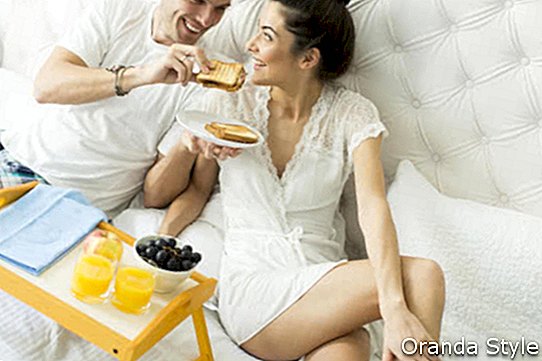 Млада двойка, закусваща в леглото