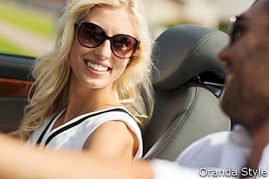 איש ואישה שמחים נוהגים במכונית קבריולט בחוץ