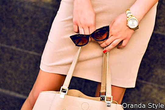 junge Geschäftsfrau, die Tasche und Retro- Sonnenbrille hält