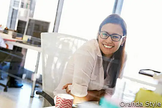Mujer en su escritorio en una oficina sonriendo a la cámara