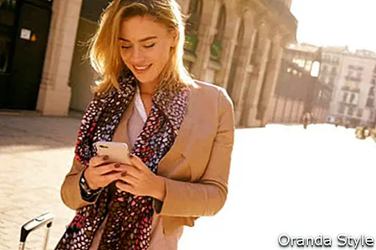 nádherná krásna mladá žena s blond vlasy správ na smartphonu na pozadí mesta ulici